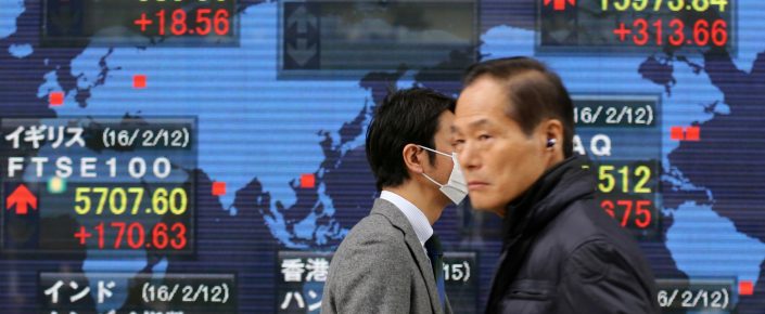 People walk by an electronic stock board of a securities firm, in Tokyo on February 15. The realization is dawning that growth may continue to underperform, while in Japan the yield on 10-year bonds briefly turned negative. (AP Photo/Koji Sasahara)